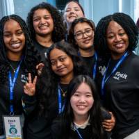 Group of event attendees standing together, giving peace signs and smiling at camera